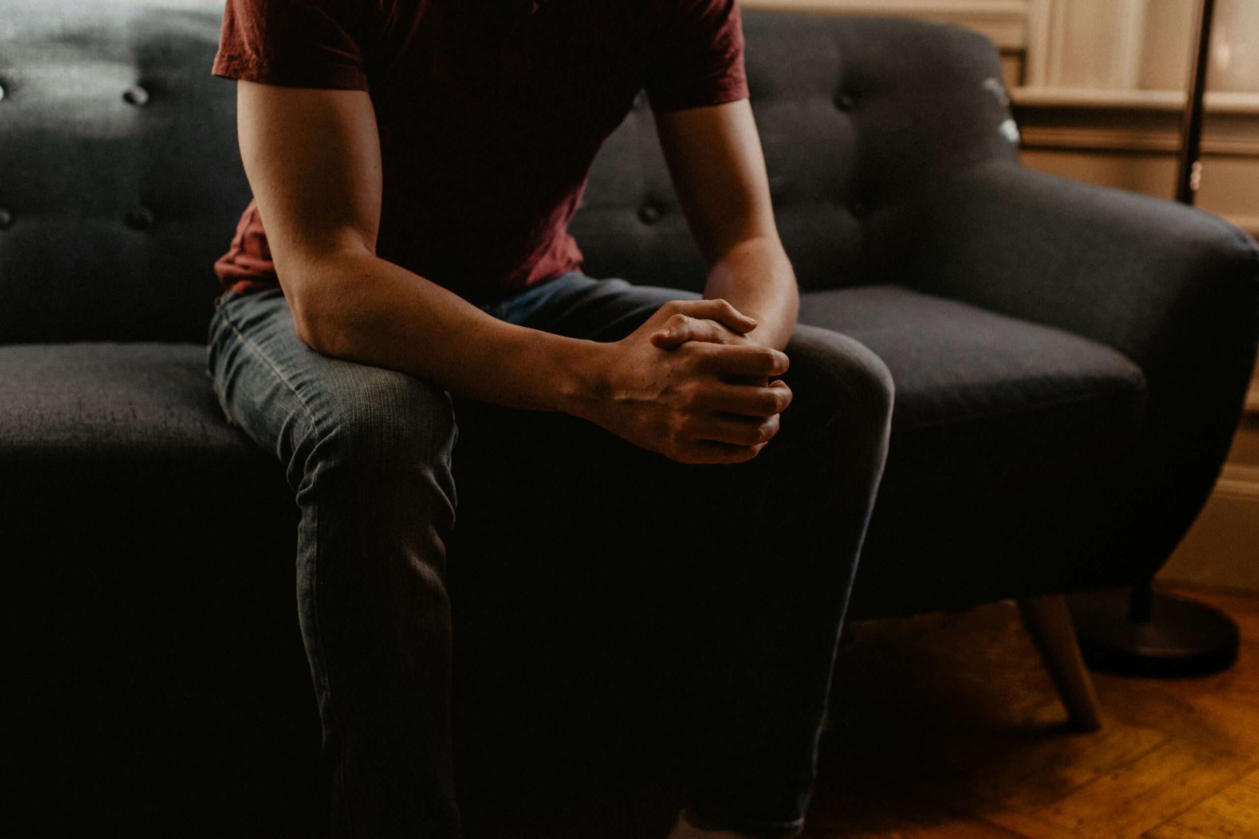 Individual seated on a sofa, reflecting during a low-cost counselling session